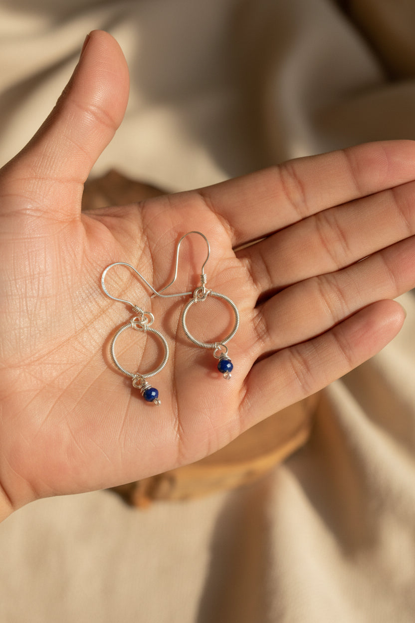 Handmade Blue Haven earrings featuring genuine blue chalcedony and silver-toned copper, displayed on a hand in natural light.
