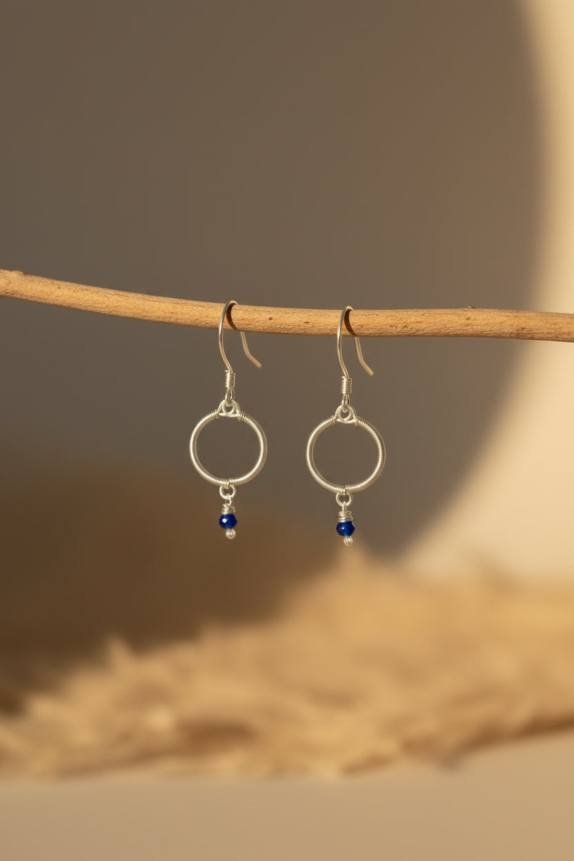 Handmade silver-toned copper circle earrings featuring genuine blue chalcedony gemstone beads, photographed in warm natural light.