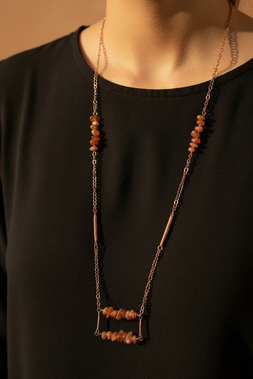 Model wearing Canyon Glow, a handmade long copper necklace featuring natural orange Carnelian gemstone chips and artisan wire-wrapped details.