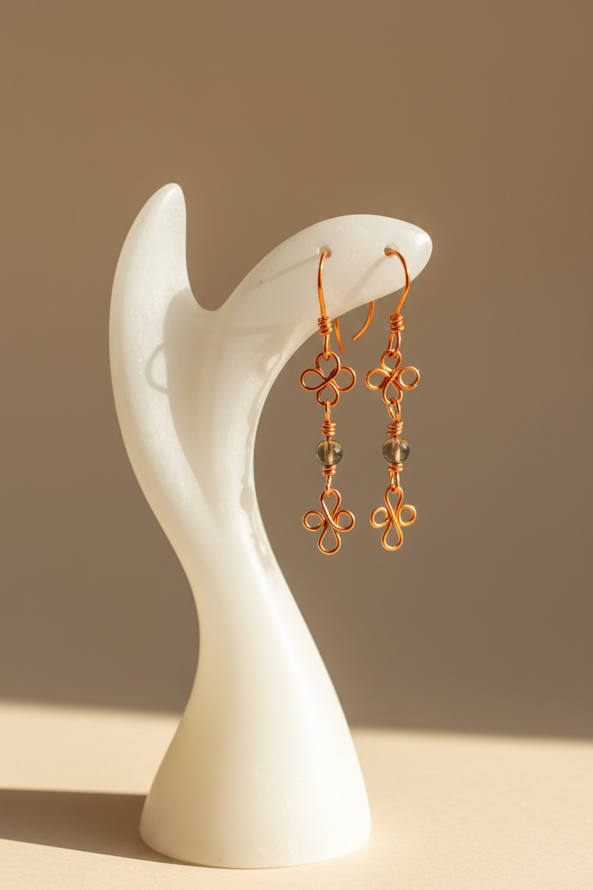 Clover-whisper-earrings copper wire earrings held by a hand against a neutral background