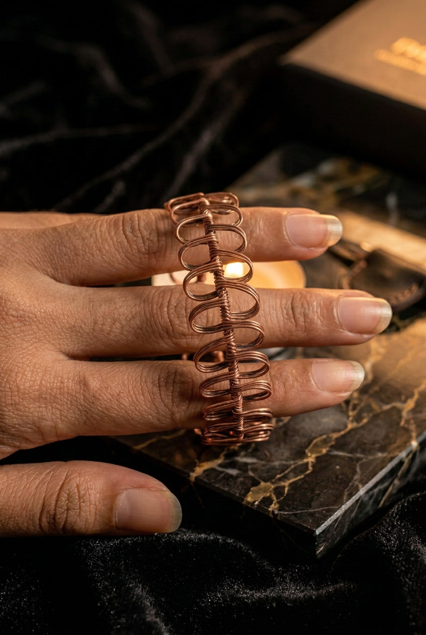Close-up of the handcrafted Copper Rhapsody copper wire bracelet featuring sculptural repeating loops.