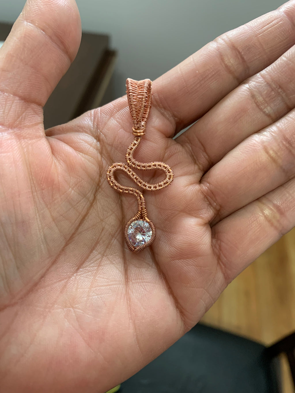 Copper Tie handcrafted copper pendant with a sparkling 8 mm zirconia resting in the palm of a hand.