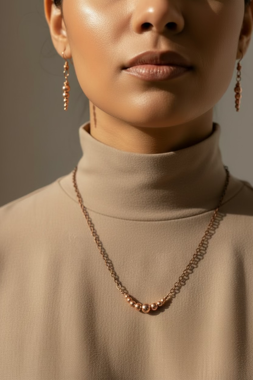 Model wearing a copper chain necklace and earrings against a neutral background