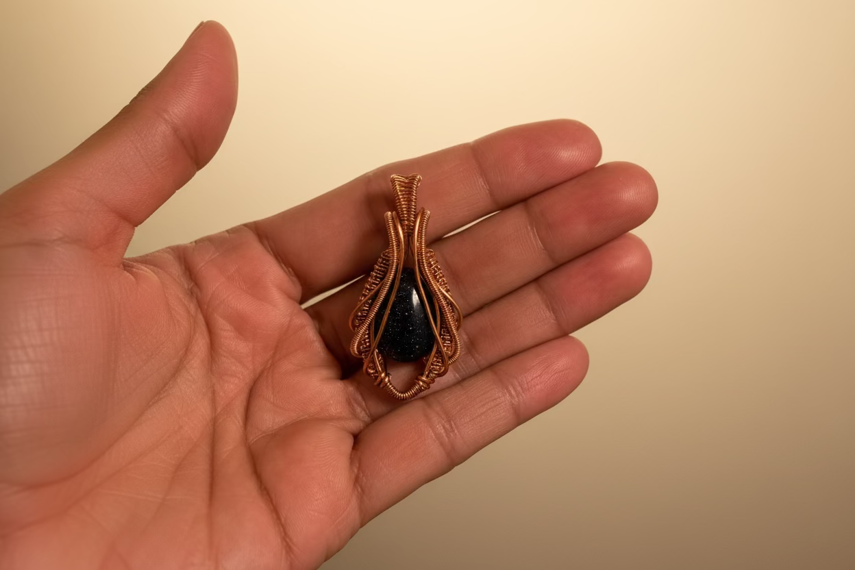 Close-up of the Cosmic Bloom handcrafted Blue Goldstone pendant featuring shimmering midnight blue stone wrapped in flowing copper wire