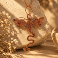 Handcrafted copper Dragon Heart pendant displayed on a rock
