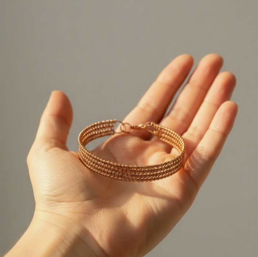 Emberloom handcrafted copper wire bracelet resting in the palm, emphasizing its detailed woven design, warm copper finish, and handmade artisan quality.