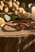 Artisan handcrafted copper cuff bracelet with mystic aura quartz displayed on rustic wood in warm natural lighting.