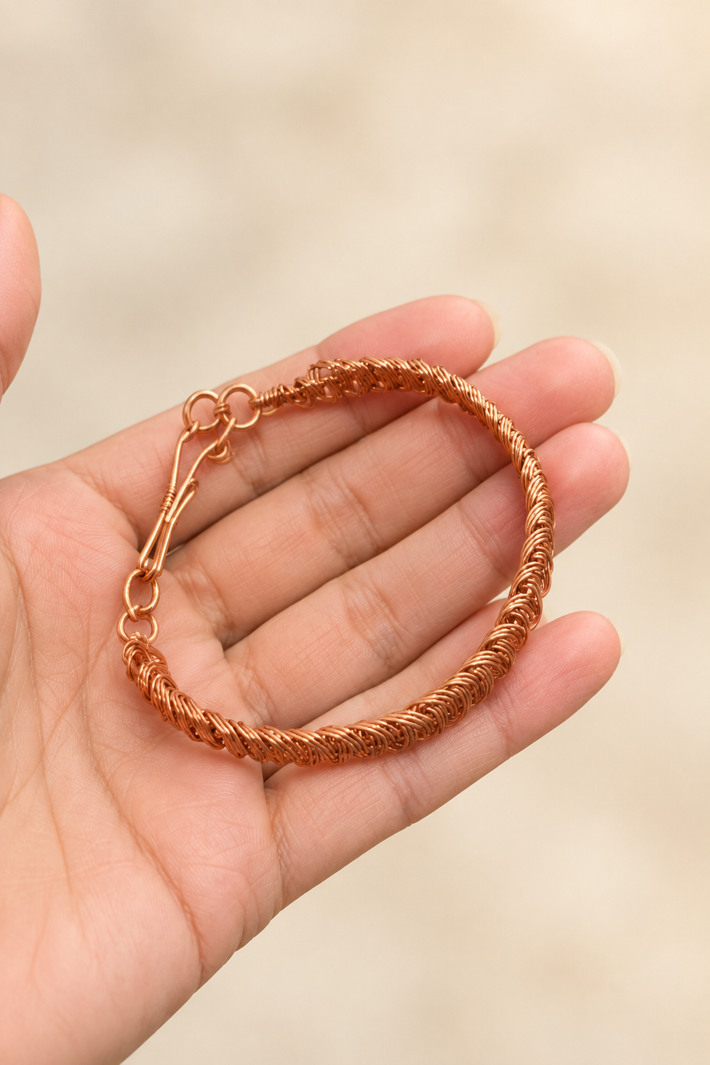 Handwoven copper bracelet displayed in palm showing intricate wirework