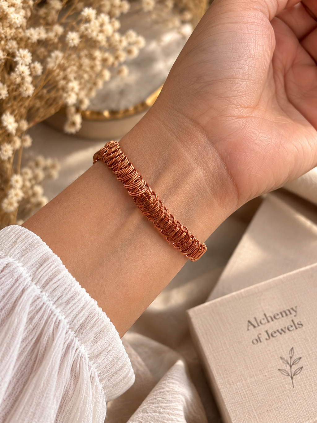 Handwoven copper bracelet worn on wrist showing detailed wire weave