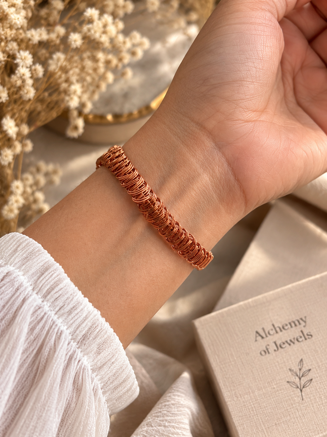 Handwoven copper bracelet worn on wrist showing detailed wire weave