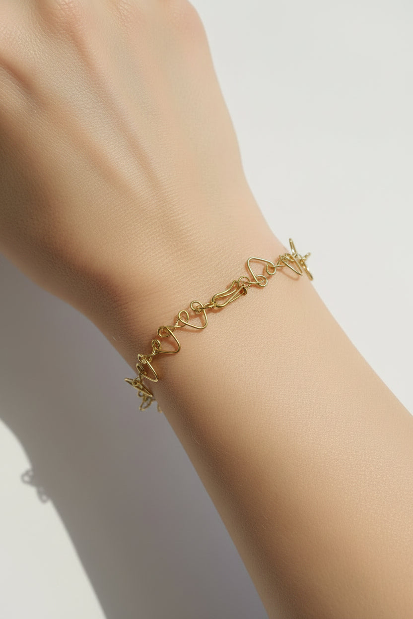 Gold  coloured bracelet with heart-shaped links on a light background