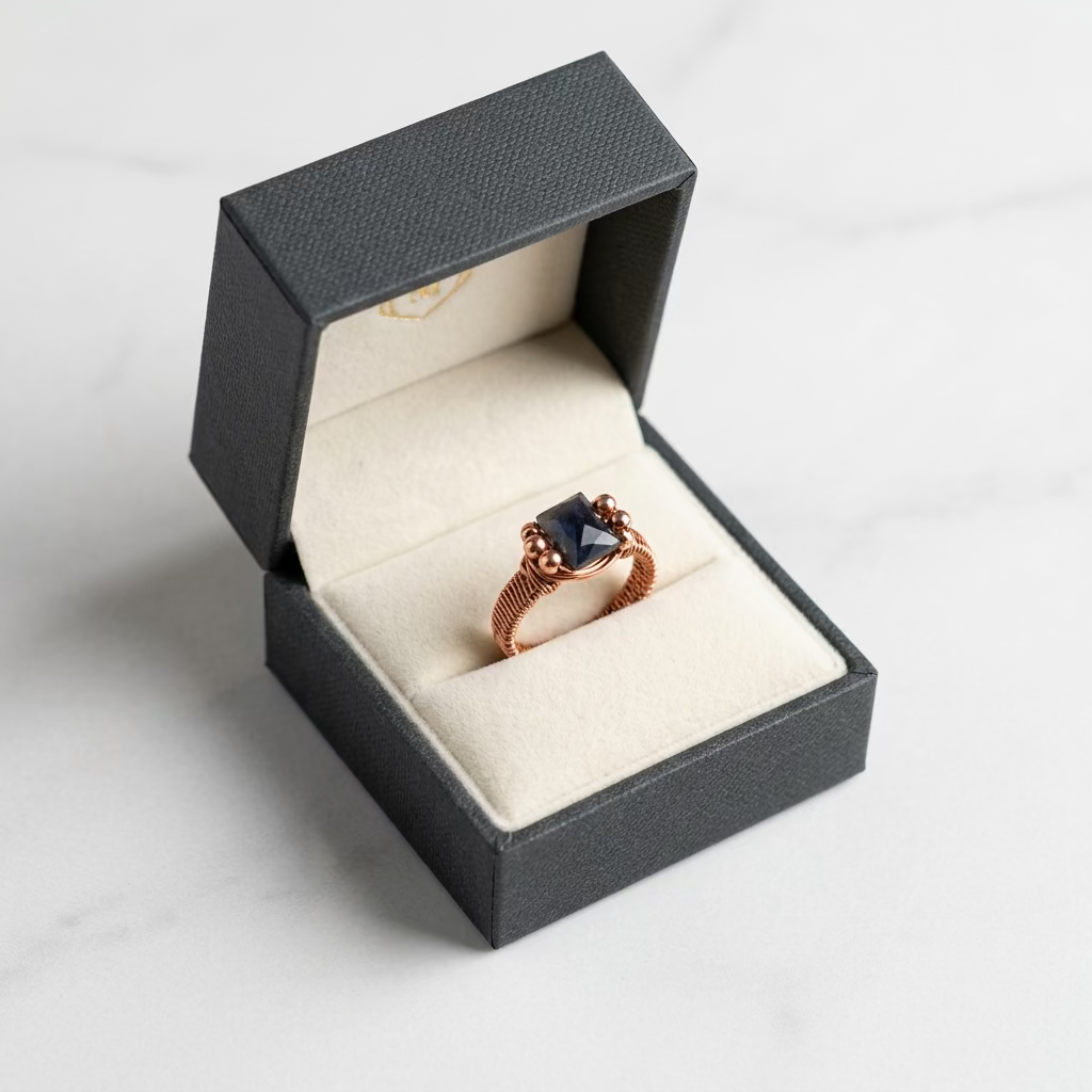 A rectangular faceted labradorite gemstone set in a textured copper wire ring with copper accent beads.