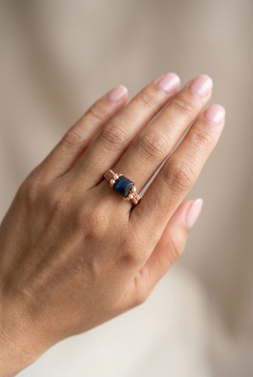 Labradorite Muse handcrafted copper ring with rectangular dark blue labradorite and copper decorative bead accents, worn on a hand.