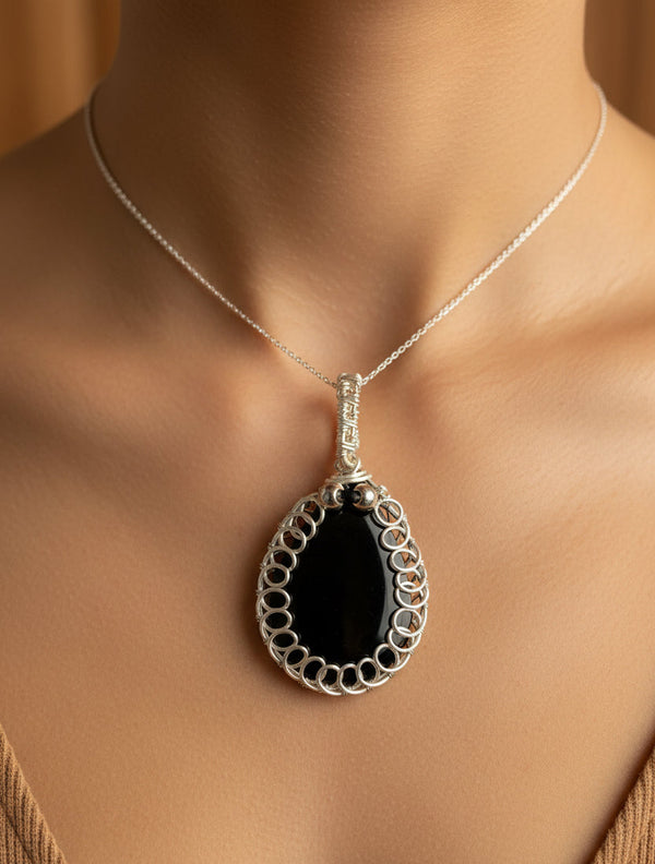 Woman wearing handmade Midnight Halo pendant featuring black resin, silver-toned copper wire, and subtle crown bead accents.