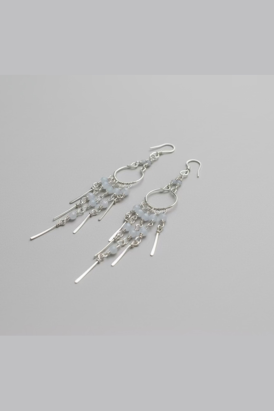 Handcrafted Moonstone Rain chandelier earrings made with natural moonstone beads and silver-toned copper wire, elegantly displayed on a lplain backround