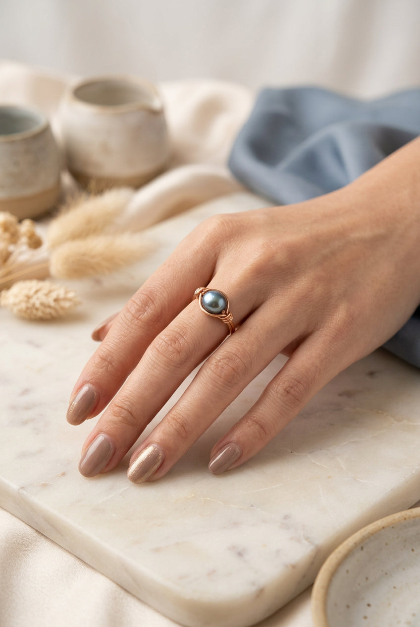 Pearl Alchemy ring featuring a single dark blue/grey pearl in a handcrafted copper wire setting.