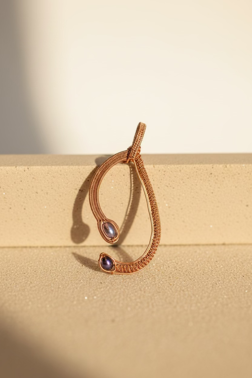 Handwoven copper pendant with two genuine freshwater pearls displayed on a soft neutral background.