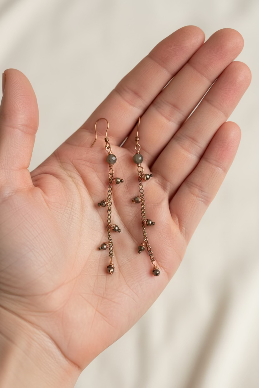 Handmade copper and pyrite dangle earrings shown in hand for size reference.