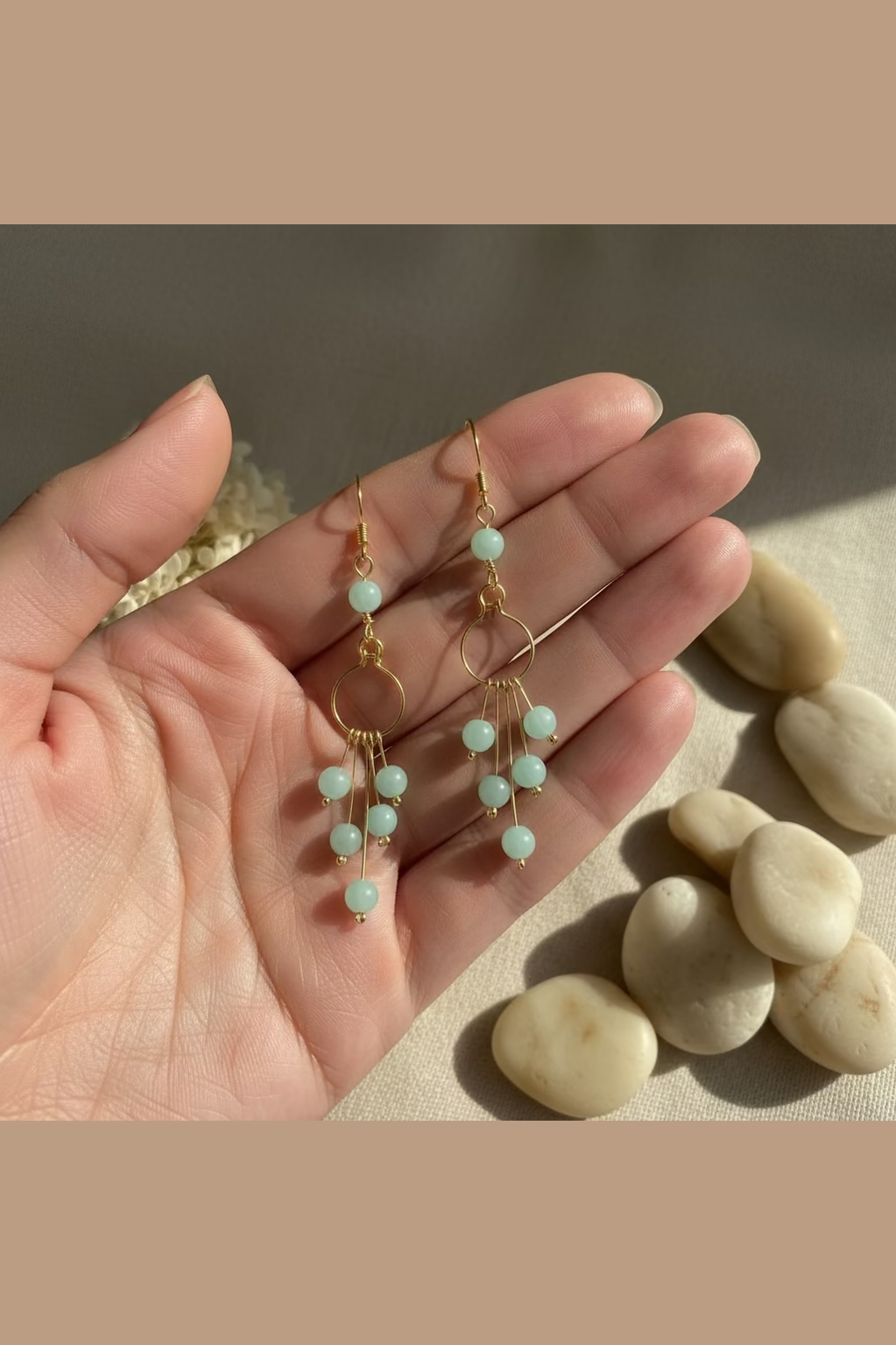 Hand holding Seafoam Serenade handmade Amazonite earrings crafted in golden-toned copper, showcasing their delicate cascading design.