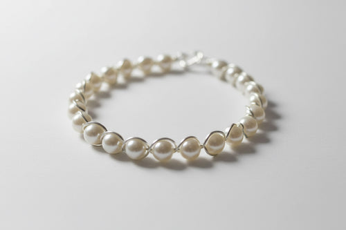 Pearl bracelet on a white surface with a dark background