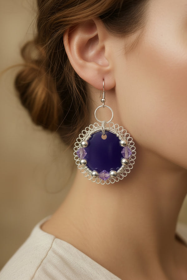 Woman wearing handmade Velvet Violet Lace Earrings featuring dark purple resin and silver-toned copper wire.